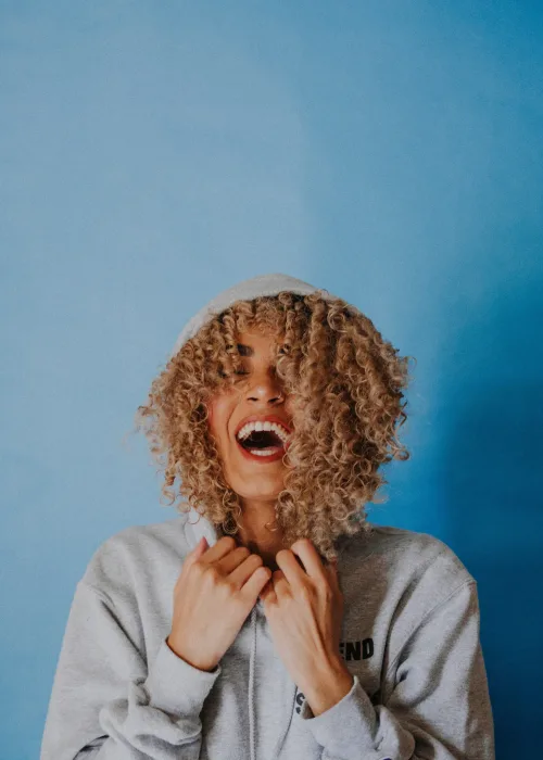 A young woman laughing happily, illustrating relief from chronic jaw tension or TMJ discomfort.