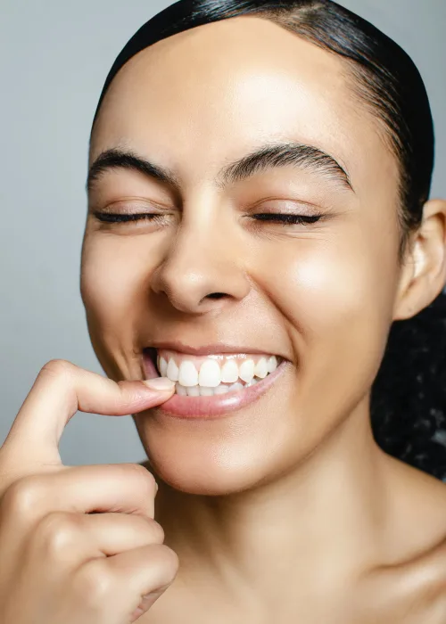 A young woman smiling while wearing a clear, discreet orthodontic aligner.