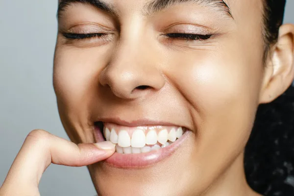 A young woman smiling while wearing a clear, discreet orthodontic aligner.